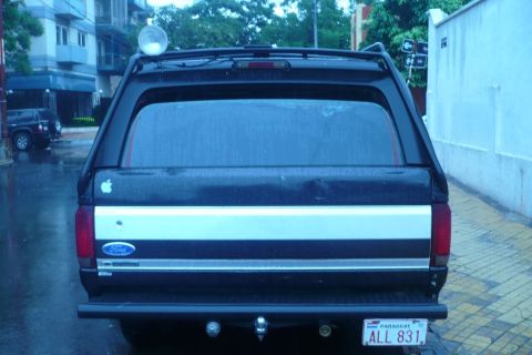 1992 Ford Bronco - Rear view of a 1992 Ford Bronco, showing its camper shell and distinctive silver stripe.