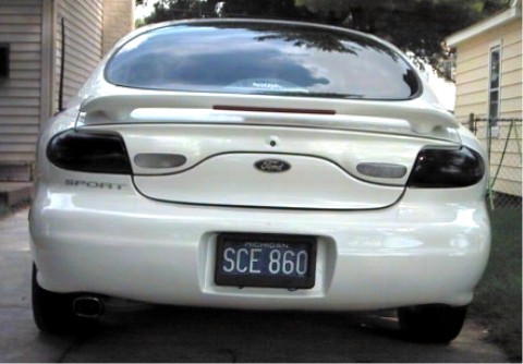 1997 Ford Taurus - Rear view of a white 1997 Ford Taurus with tinted taillights and a spoiler.