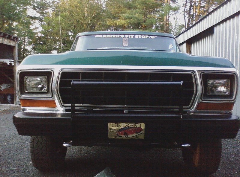 Green truck front with black grille, bumper, and license plate reading 'The Legend'