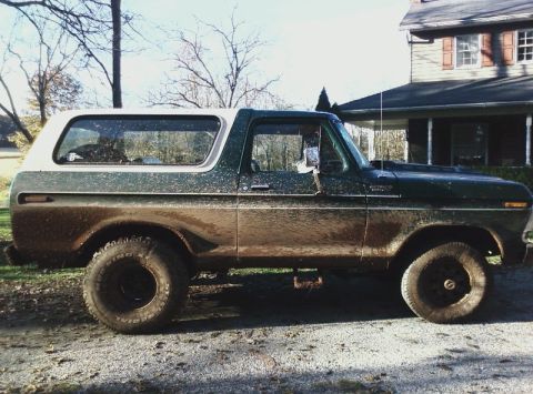 1979 Ford Bronco - A muddy 1978 Ford Bronco sits parked on a gravel surface next to a house.