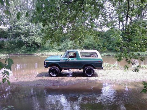 1979 Ford Bronco - 1978 Ford Bronco parked on the edge of a body of water surrounded by trees.