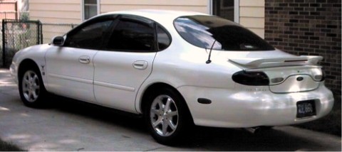 1997 Ford Taurus - Rear view of a white sedan with a spoiler and tinted windows, parked on a driveway.