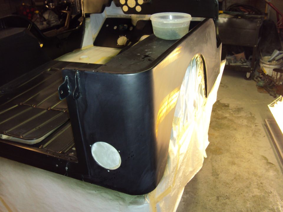 Black Jeep CJ-5 rear quarter panel and bed, undergoing restoration, with a clear plastic tub on top