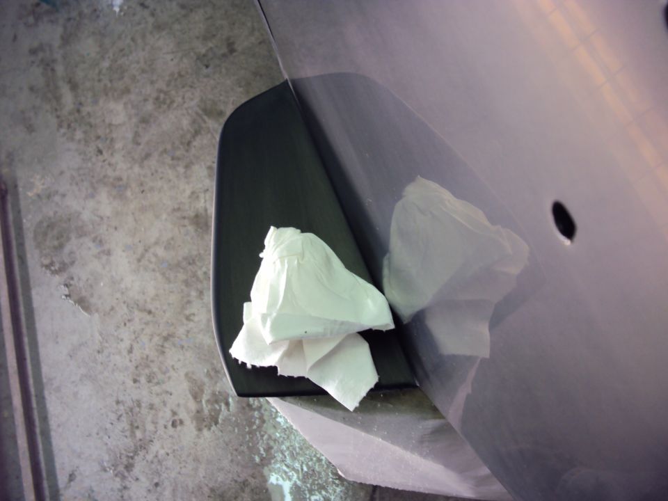 Close-up of a car's door panel with a black trim piece and white paper towels on it