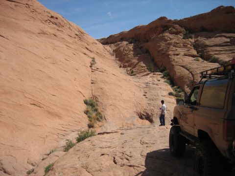 1986 Ford Bronco II - A person stands next to an off-road vehicle on a rocky path in a desert landscape.
