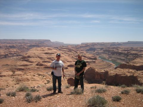 1986 Ford Bronco II - Two men overlook a wide canyon landscape with a river winding through it. Supermotors.net logo is present.