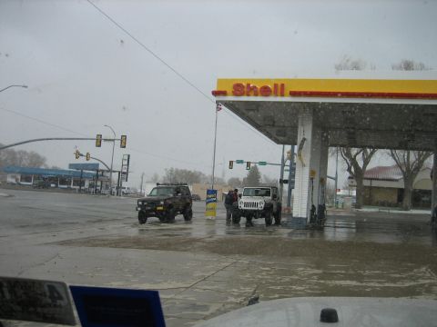 1986 Ford Bronco II - Two off-road vehicles are parked under a Shell gas station canopy during a snowfall.