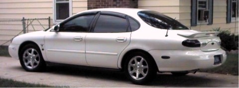 1997 Ford Taurus - Side view of a white 1997 Ford Taurus sedan with aftermarket wheels.