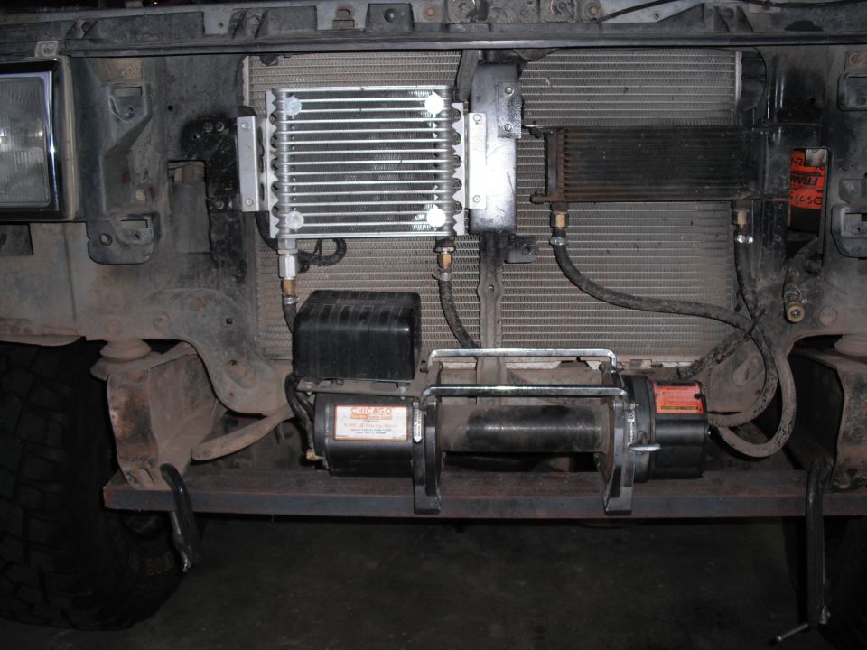 Winch mounted in front of radiator and oil cooler with visible hoses and wiring