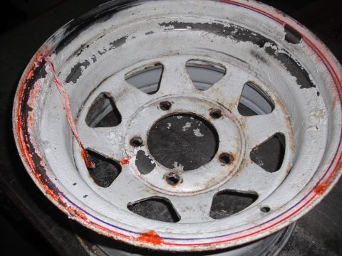 1991 Ford Bronco - A close-up view of a damaged white wheel rim with visible rust and peeling paint.
