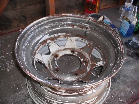 1991 Ford Bronco - A wheel with peeling white paint and rust is shown, with cleaning supplies in the background.