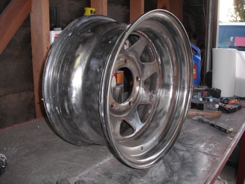 1991 Ford Bronco - A single aluminum wheel is shown on a workbench, possibly undergoing restoration or cleaning.
