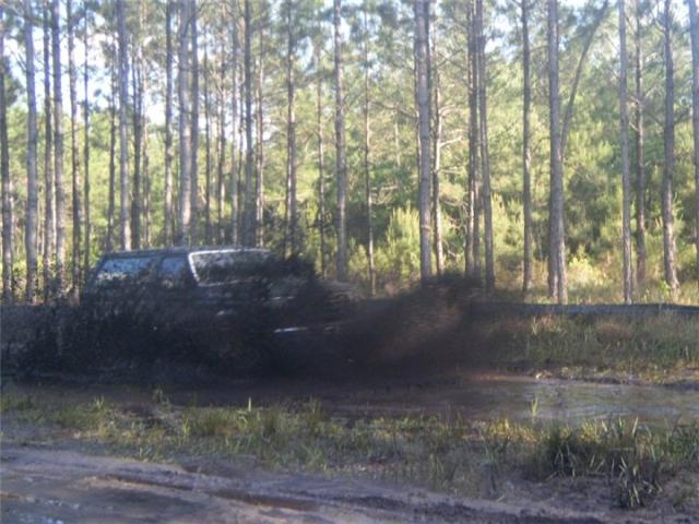 SUV splashing through mud in a forest