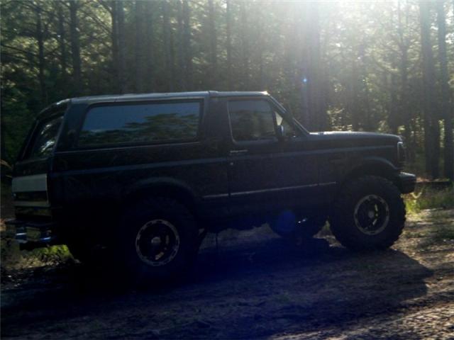 1994 Ford Bronco parked on a dirt road in a forest
