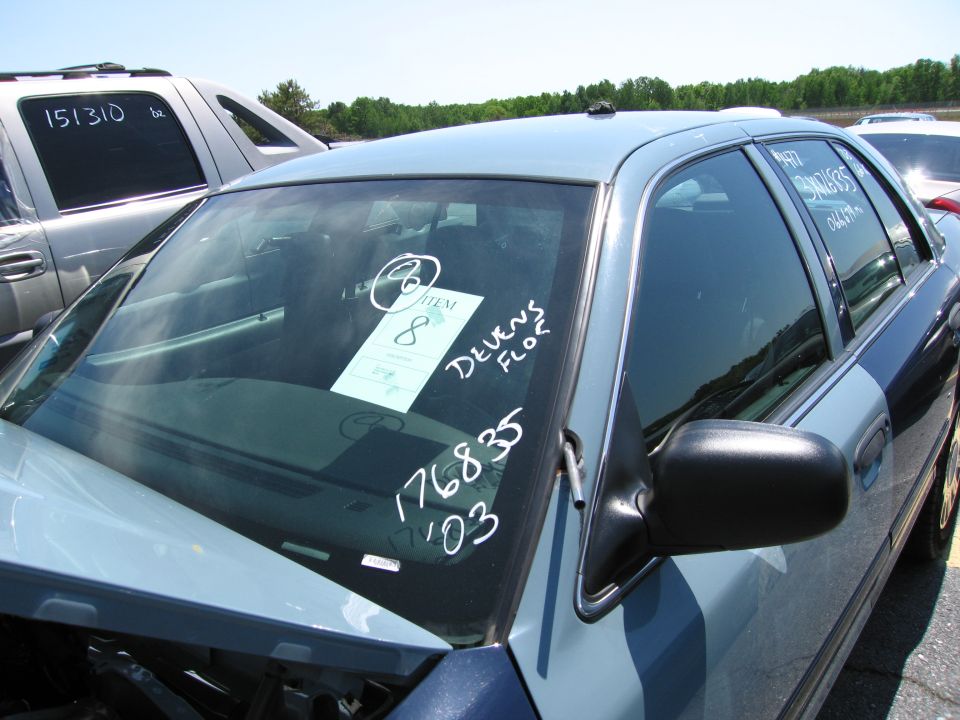 Light blue and dark blue two-tone Ford Crown Victoria, front passenger side view, with windshield paper and writing