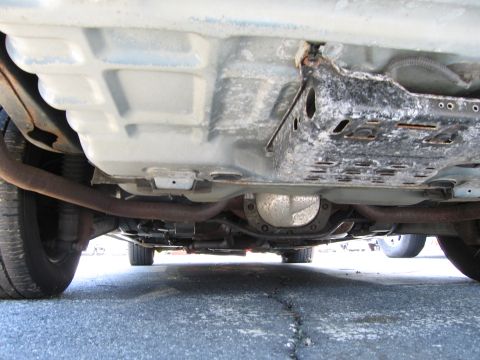 1991 Ford LTD Crown Victoria - The undercarriage of a vehicle shows the differential, exhaust pipes, and frame components.