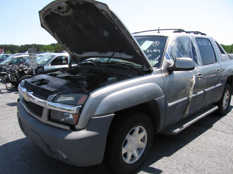 Silver SUV with hood open, plastic sheeting on passenger door, parked in a lot with other vehicles