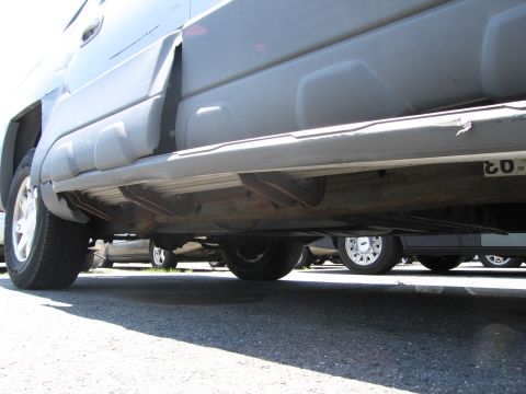 1991 Ford LTD Crown Victoria - A low-angle view of a vehicle's undercarriage, with other cars parked nearby.