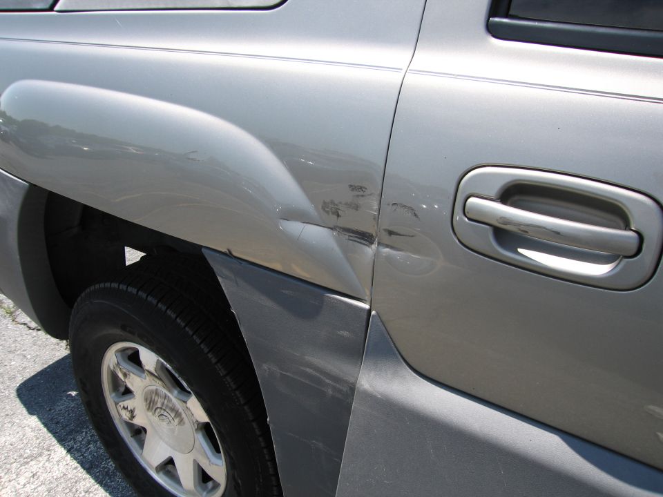Silver SUV rear quarter panel dented near door handle