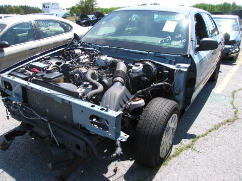 1991 Ford LTD Crown Victoria - A blue sedan is shown from the front with its hood open, revealing the engine compartment. A tag on the windshield has handwritten numbers.