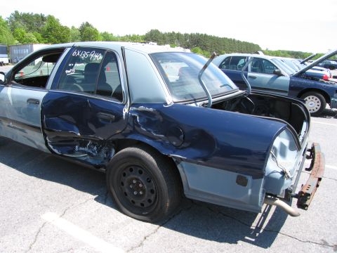 1991 Ford LTD Crown Victoria - This sedan has significant damage to its rear quarter panel and door. Another car is parked behind it.