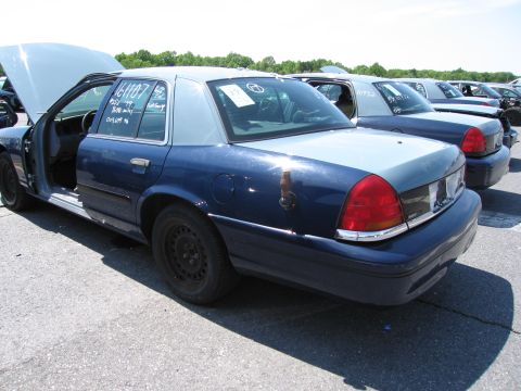1991 Ford LTD Crown Victoria - A blue and light blue Ford Crown Victoria police car sits in a lot with its hood and driver's door open.