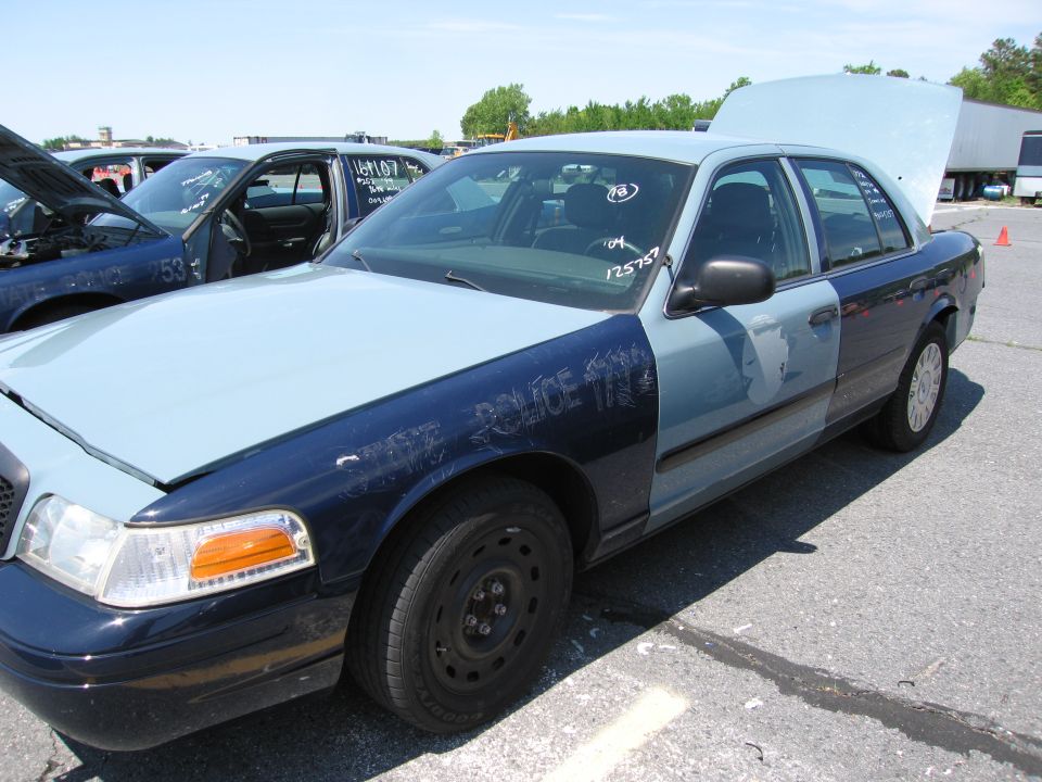 Police car with two-tone paint, hood and trunk open. Scratched text on fender