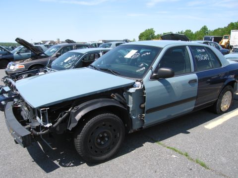 1991 Ford LTD Crown Victoria - This two-tone sedan has significant damage to its front end and appears to be in a junkyard.