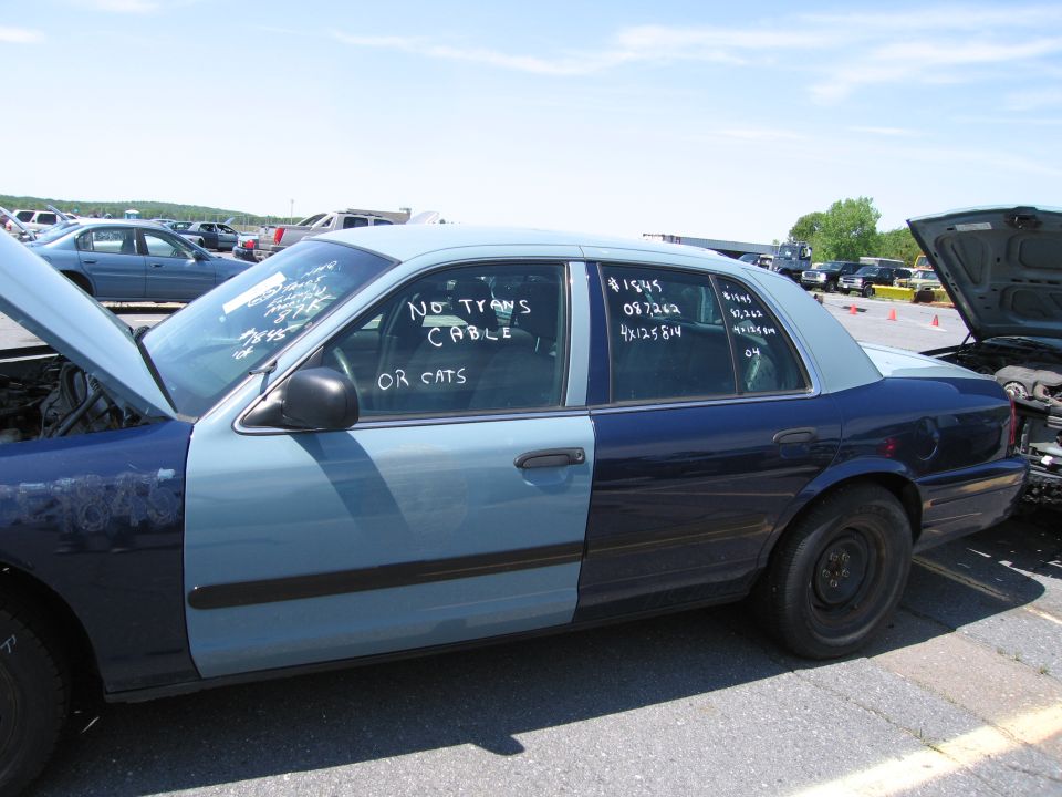 Two-tone sedan with hood open, text on windows says 'NO TRANS CABLE OR CATS'