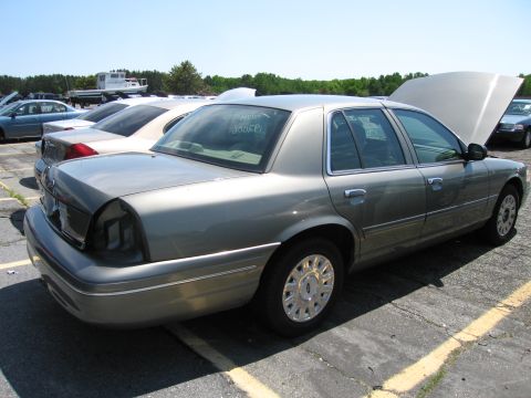 1991 Ford LTD Crown Victoria - Side view of a gray Ford Crown Victoria with its hood up, parked in a lot with other vehicles.