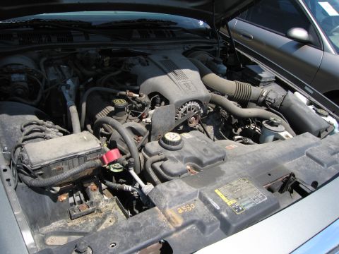 1991 Ford LTD Crown Victoria - The engine bay of a 1991 Ford Crown Victoria LTD is visible, with another car in the background.