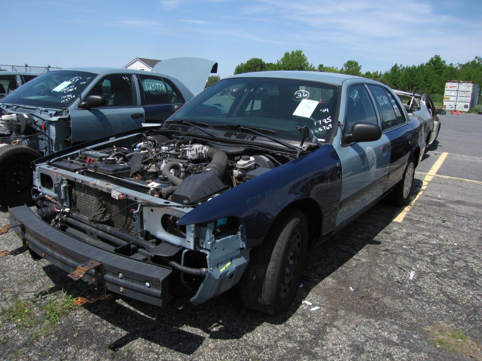 Blue and gray Ford Crown Victoria with hood open, showing engine and missing front bumper