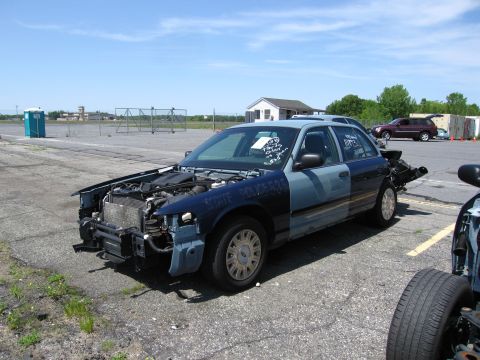 1991 Ford LTD Crown Victoria - A damaged police car sits in an open lot, showing signs of significant wear and tear.