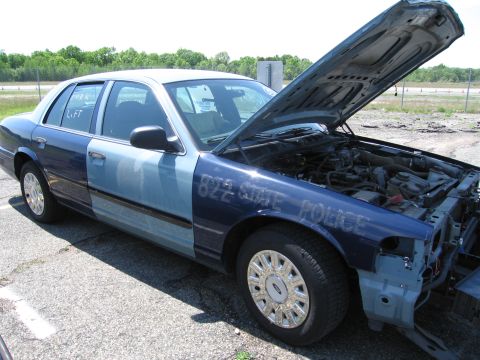 1991 Ford LTD Crown Victoria - A two-tone police car, dark blue and light blue, has its hood open revealing the engine compartment. Text on the fender reads "822 State Po…