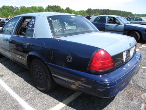 1991 Ford LTD Crown Victoria - A two-tone Ford Crown Victoria is parked in a lot with other vehicles. Text is written on the rear window.
