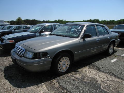 1991 Ford LTD Crown Victoria - A gray Ford Crown Victoria is parked in a lot with other vehicles under a clear sky.