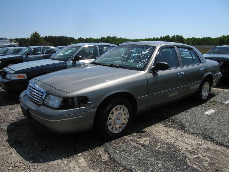 Gray Ford Crown Victoria with missing headlight, parked outdoors