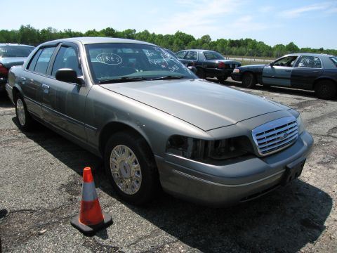 1991 Ford LTD Crown Victoria - A gray Ford Crown Victoria sits in a lot, missing its headlights, with other vehicles in the background.