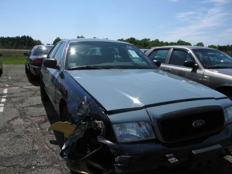 1991 Ford LTD Crown Victoria - A damaged Ford Crown Victoria sits in a lot next to other vehicles under a clear sky.