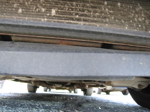 1991 Ford LTD Crown Victoria - The undercarriage of a vehicle is visible, with suspension parts and the road below.