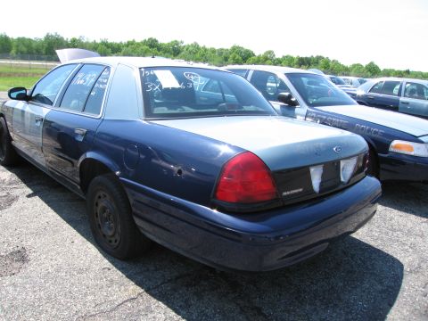 1991 Ford LTD Crown Victoria - Two police cars are parked in an outdoor lot, one in the foreground and another behind it.