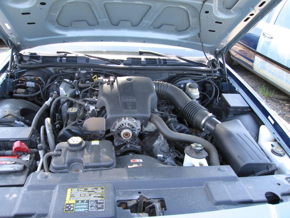 Engine bay of a Ford Crown Victoria. Shows the V8 engine, air intake, battery, and coolant reservoir