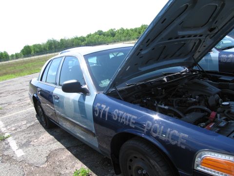 1991 Ford LTD Crown Victoria - A police car with its hood open reveals the engine compartment, with visible markings on the fender.