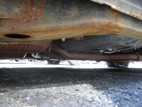 1991 Ford LTD Crown Victoria - The underside of a vehicle shows significant rust on the frame and exhaust system.