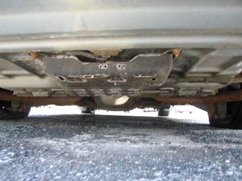 1991 Ford LTD Crown Victoria - The underside of a vehicle reveals rusted exhaust components and a differential assembly.