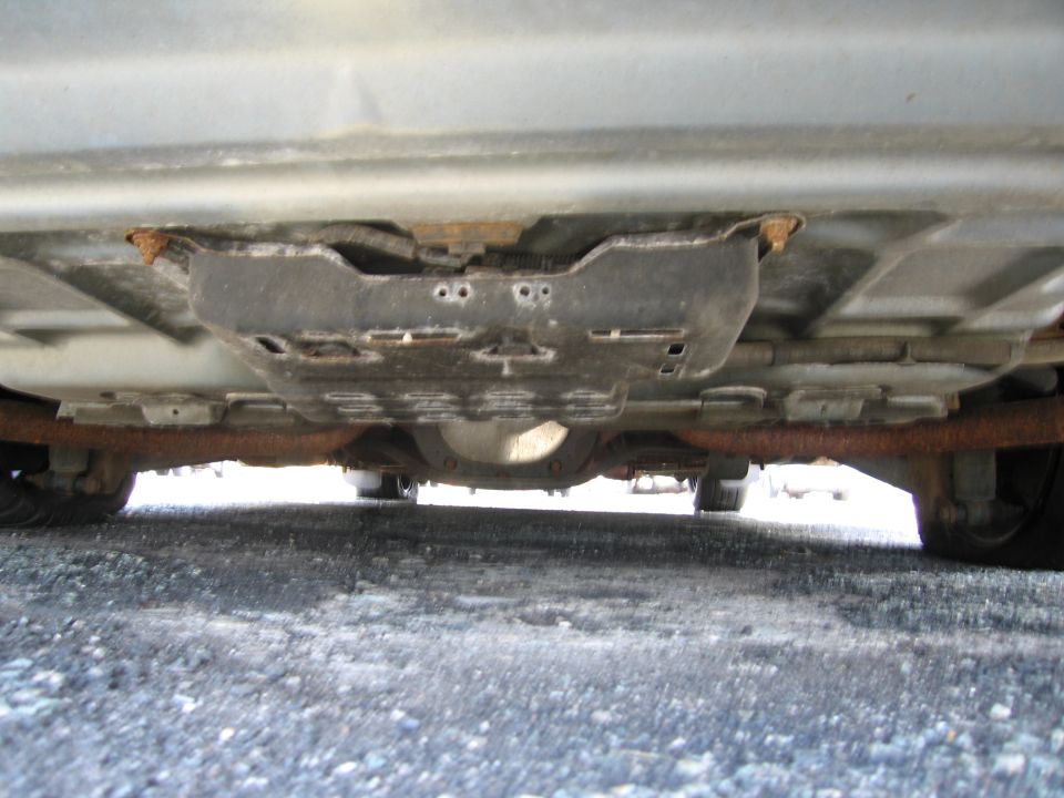 Underside of a car showing rusted exhaust pipes and a differential