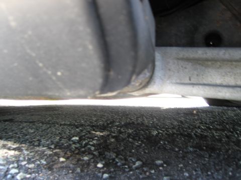 1991 Ford LTD Crown Victoria - A close-up view of a vehicle's undercarriage, focusing on suspension parts and a tire, with gravel visible below.