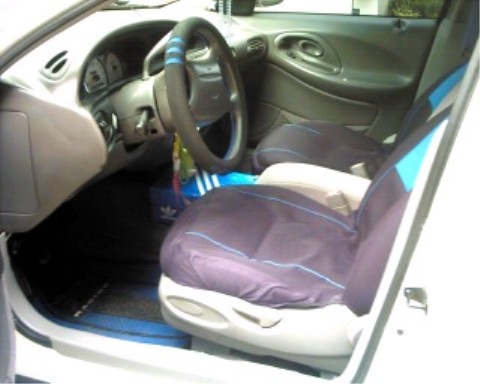 1997 Ford Taurus - Interior view of a 1997 Ford Taurus, showing the dashboard, steering wheel, and front seats with custom covers.