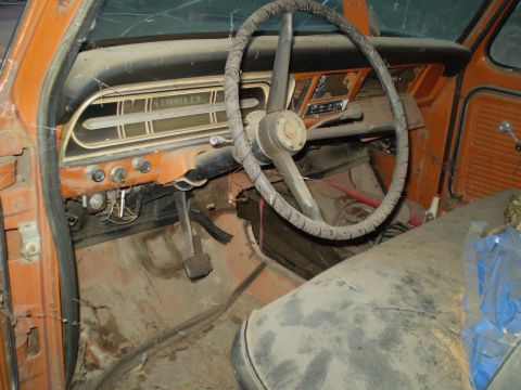 1969 Ford F-250 - The interior of this truck is covered in dust, with visible wear on the steering wheel and dashboard.