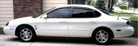 1997 Ford Taurus - Side view of a white 1997 Ford Taurus sedan with a rear spoiler.
